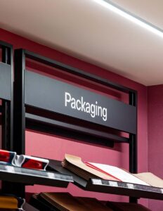 Packaging section with shelves displaying various paper products in a retail store setting.