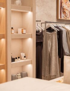 Modern retail display with illuminated shelves, skincare products, and clothing rack with neutral-toned apparel.