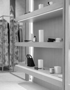 Modern retail display with shelves showcasing sunglasses, boxes, perfume, and accessories in a fashion store.