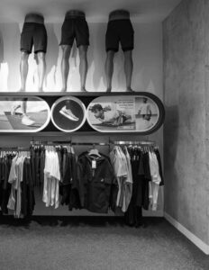 Mannequin legs wearing shorts above clothing display in retail store; sportswear and casual apparel showcase.