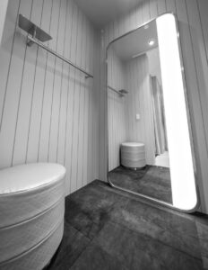 Modern changing room with full-length mirror, cushioned bench, minimalist design, and lighting for enhanced viewing.