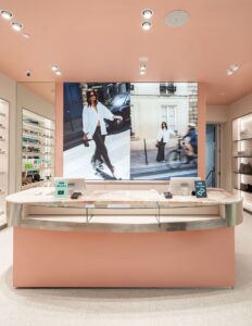 Modern cosmetic store counter with large fashion photo display, sleek design, and illuminated product shelves.