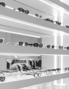 Sunglasses displayed on modern white shelves with LED lighting in stylish eyewear store.