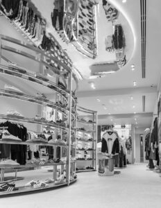 Modern sneaker and apparel store with sleek shelves and mirrored ceiling reflection.